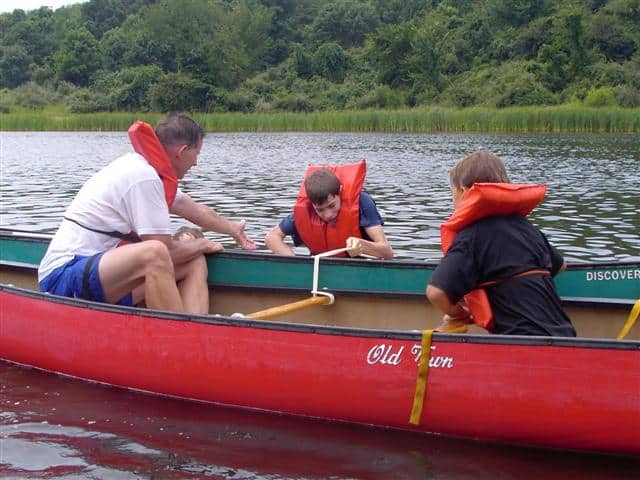 Rescuers stabilizing canoe while pulling a boy back into it