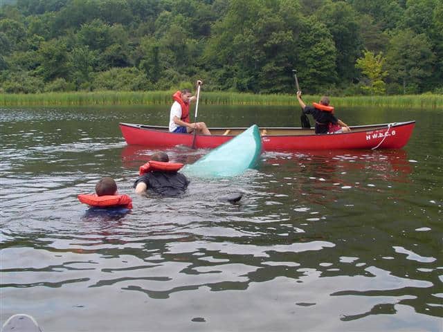 Lining up flipped canoe in the water with rescue boat