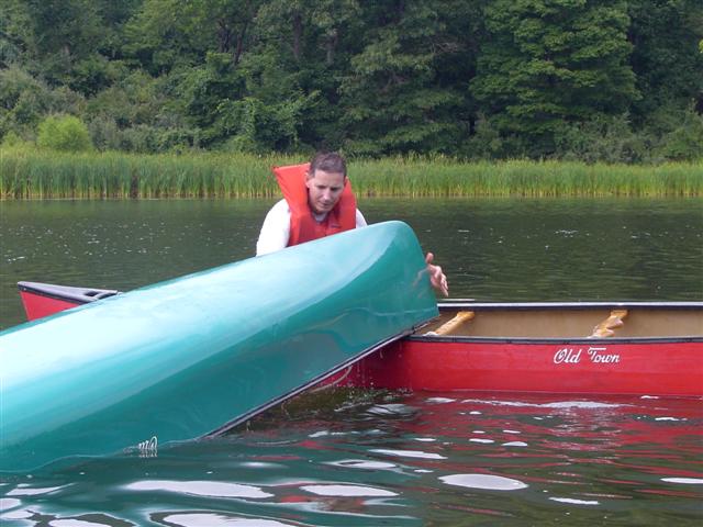 Bow of upside-down canoe lifting onto rescue boat