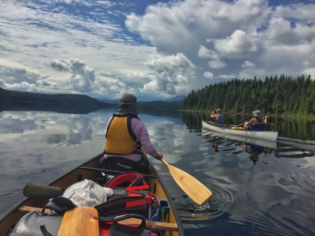 Two canoes headed off along a mountain lake
