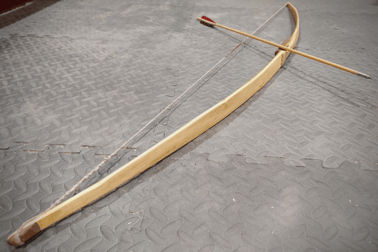 Black Locust bow with black walnut and hickory accents, and a hemp string lying on the floor